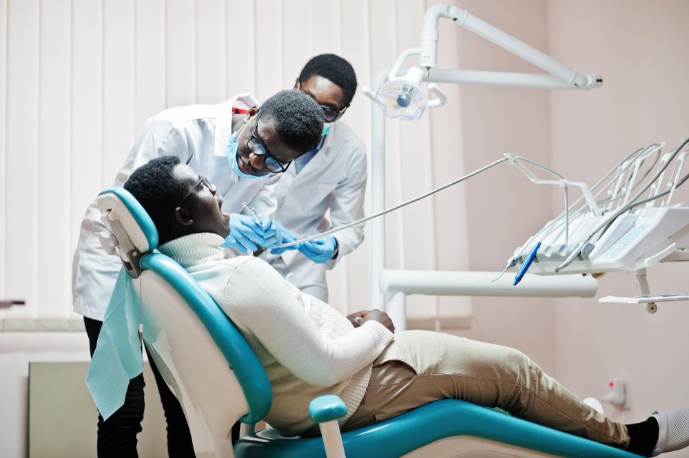 Dentist explaining a treatment plan to a patient and her companion at a Kenyan clinic